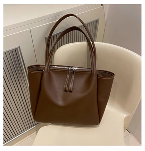 Detail view of dark brown tote bag showing contrast white stitching and metal zippers