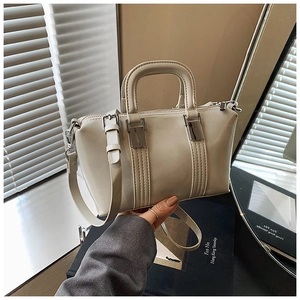 Detail of beige crossbody handbag with silver hardware and a thick top handle grip
