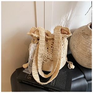 Close-up of handmade woven straw bucket bag with lace ribbon and drawstring closure