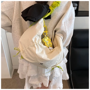 Détail du sac croissant blanc cassé avec cordon vert fluo et décoration de breloque fleurie