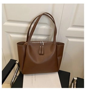 Close-up of brown leather tote bag detailing white stitching and silver hardware accents