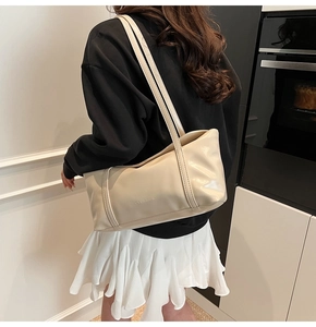 Close-up of cream beige glossy PU leather handbag with long shoulder straps on a model