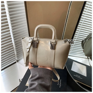 Detailed close-up of cream PU leather handbag with square metal buckle and round handles