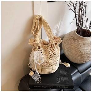 Detailaufnahme der beigen Häkel-Eimertasche mit Spitzen-Perlen-Schleife und Kordelzugfutter