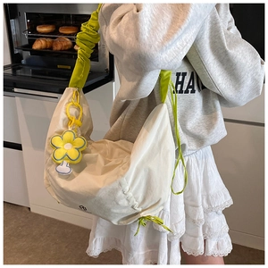 Détail du sac blanc avec bandoulière plissée verte et pendentif fleur jaune décoratif
