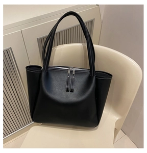 Detail view of large black tote bag featuring contrast stitching and dual zipper design