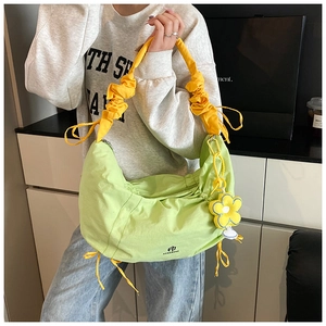 Détail du sac à plis vert citron avec bandoulière à volants jaunes et breloque fleur