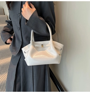 Detailansicht einer weißen Henkeltasche mit Seitenteilen und goldener Metallschnalle