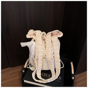 Detail of cream woven bucket bag showing lace trim and drawstring closure on books
