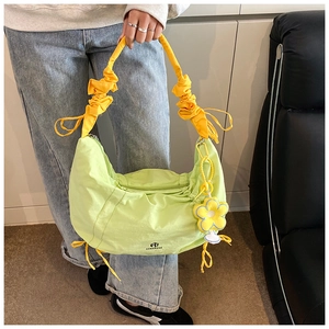Détail du sac fourre-tout vert clair avec bandoulière froncée jaune et fleur bleue