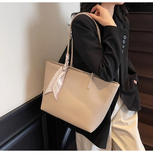 Detail of lychee textured beige tote bag featuring an elegant pink checkered scarf wrap handle