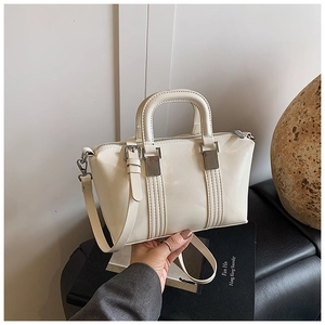 Close-up of cream Boston handbag featuring glossy leather texture and silver hardware