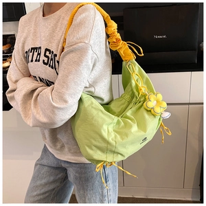 Détail du sac hobo vert clair avec bandoulière plissée jaune et pendentif tournesol