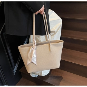Detail view of large beige tote bag with litchi texture and houndstooth scarf
