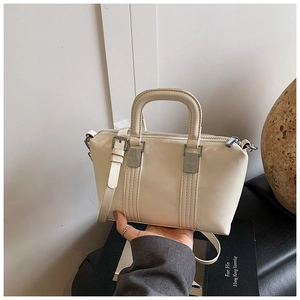 Detailed close-up of a beige crossbody bag with double handles and silver metal hardware
