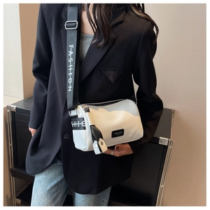 Détail d'un sac bandoulière en cuir blanc avec large sangle logo et patch mode en cuir