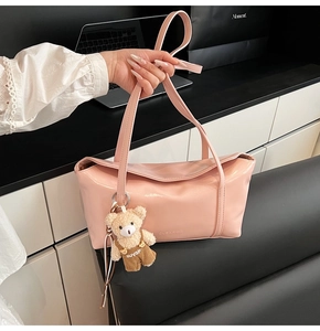 Detail of pink glossy faux leather shoulder bag with plush bear charm and embossed logo