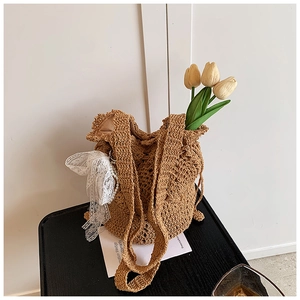 Detail of camel hollow crochet shoulder bag with white lace bow and floral accent
