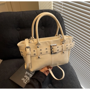 Dettaglio della borsa tote in pelle PU beige con occhielli metallici su sedia nera