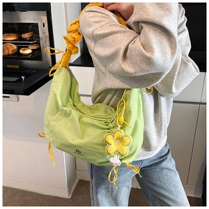 Sac croissant vert avec bandoulière plissée jaune et breloque fleurie sur un mannequin