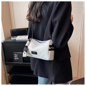 Détail du sac polochon en cuir grainé blanc avec étiquette mode et large bandoulière