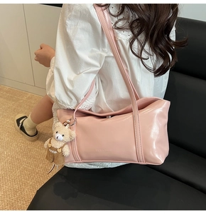 Detailed texture of pink shoulder bag with minimalist logo and cute bear pendant