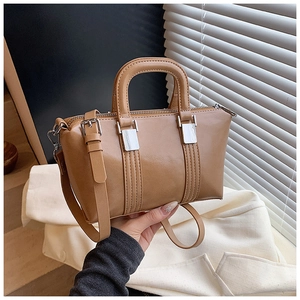 Detail of a brown polished Boston handbag with dual handles and adjustable shoulder strap