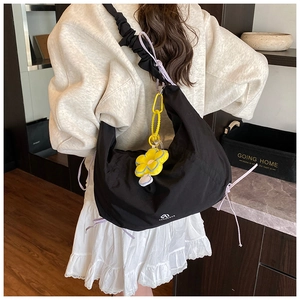Détail du sac hobo en nylon noir avec bandoulière plissée et breloque tournesol jaune