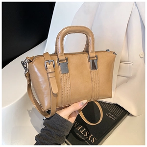 Macro shot of khaki leather handbag showing metallic buckles and stitching details