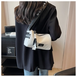 Vue détaillée d'un sac bandoulière blanc grainé avec une large sangle en nylon noir
