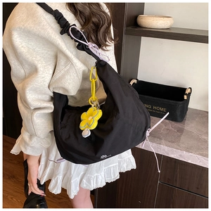 Détail du sac dumpling en nylon noir plissé avec cordon violet et charm fleur jaune