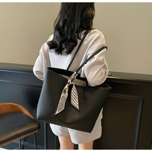 Detail of black pebbled leather tote bag with stylish geometric floral silk scarf handle
