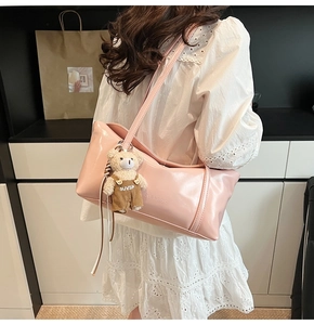 Pink patent leather shoulder bag detail with plush bear charm and embossed logo