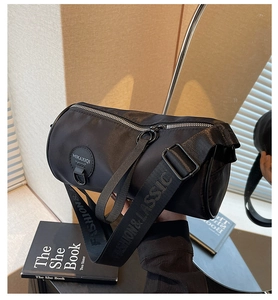 Detail of black cylindrical crossbody bag with logo leather patch and branded strap