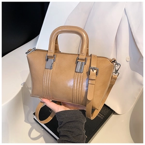 Detail of a khaki Boston handbag featuring smooth leather texture and silver metal hardware