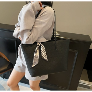 Detail of black pebbled leather tote bag with elegant floral scarf on the shoulder strap