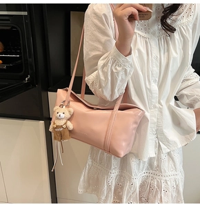 Detail of light pink tote bag with bear charm and CLEAROK logo on a female model
