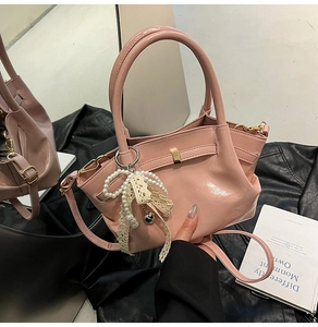 Rosa glänzende Handtasche mit elegantem Anhänger aus Perlen und Spitzenschleife