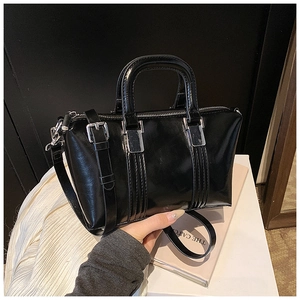 Close-up of black glossy leather Boston bag with vertical stitching and silver hardware