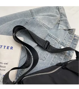 Detail of black nylon cylinder bag with adjustable FASHION strap and silver metal zipper