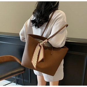 Detail view of large brown pebble leather tote bag with a chic geometric print scarf