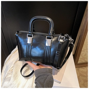 Detail of glossy black leather handbag showing silver hardware and sleek texture