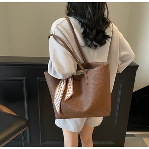 Brown lychee leather tote bag with silk scarf accessory shown on shoulder for daily commute
