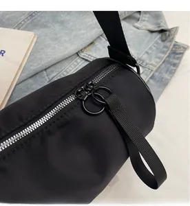 Detail shot of smooth double metal zippers on a black nylon cylinder crossbody bag