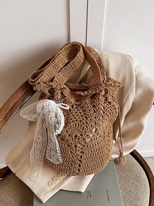 Brown crochet straw bucket bag with white lace bow and pearl charm for beach vacations