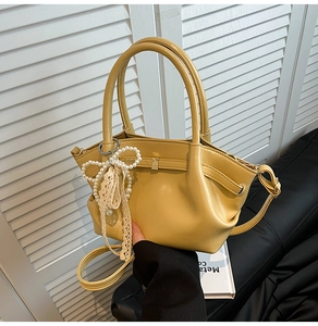 Detailaufnahme der gelben Cloud-Tasche mit Perlenbogen und feinem Spitzenband