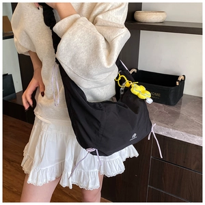 Détail du sac bandoulière plissé noir avec cordon violet et breloque fleur jaune
