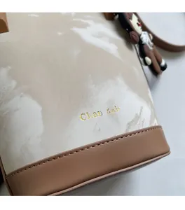 Détail du tissu effet marbre avec base en cuir marron et logo doré sur le sac seau