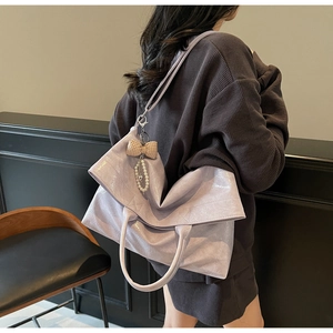 Detail of light purple pleated leather tote bag with pearl bow charm and wide shoulder strap