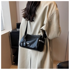 Détail du sac polochon en cuir noir grainé avec bandoulière large et étiquette logo